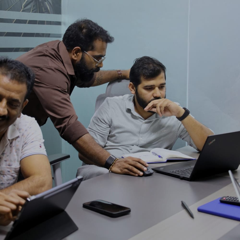 Two mentors helping a student at a laptop